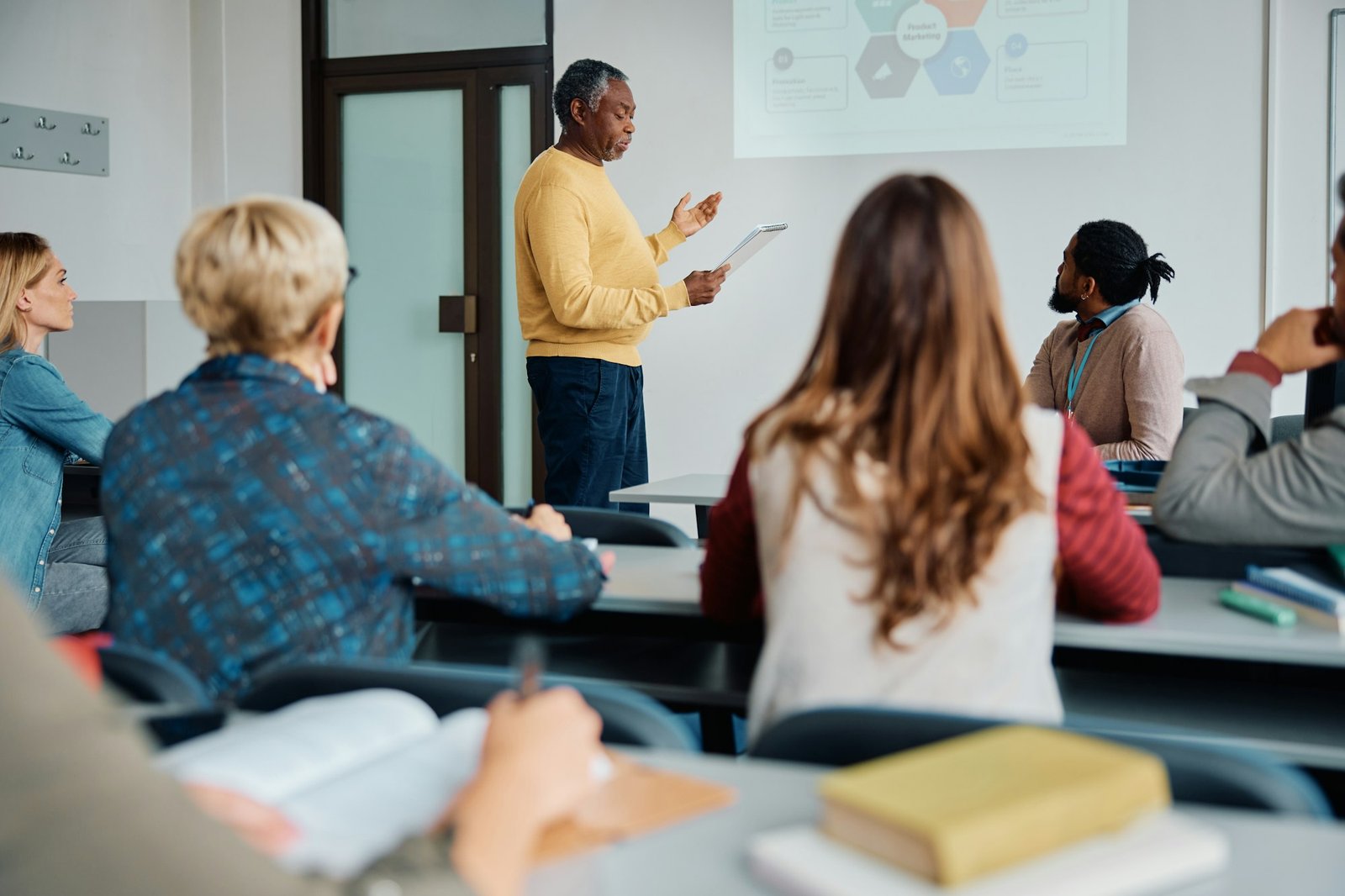 Black senior man giving a presentation during education training class in lecture hall.