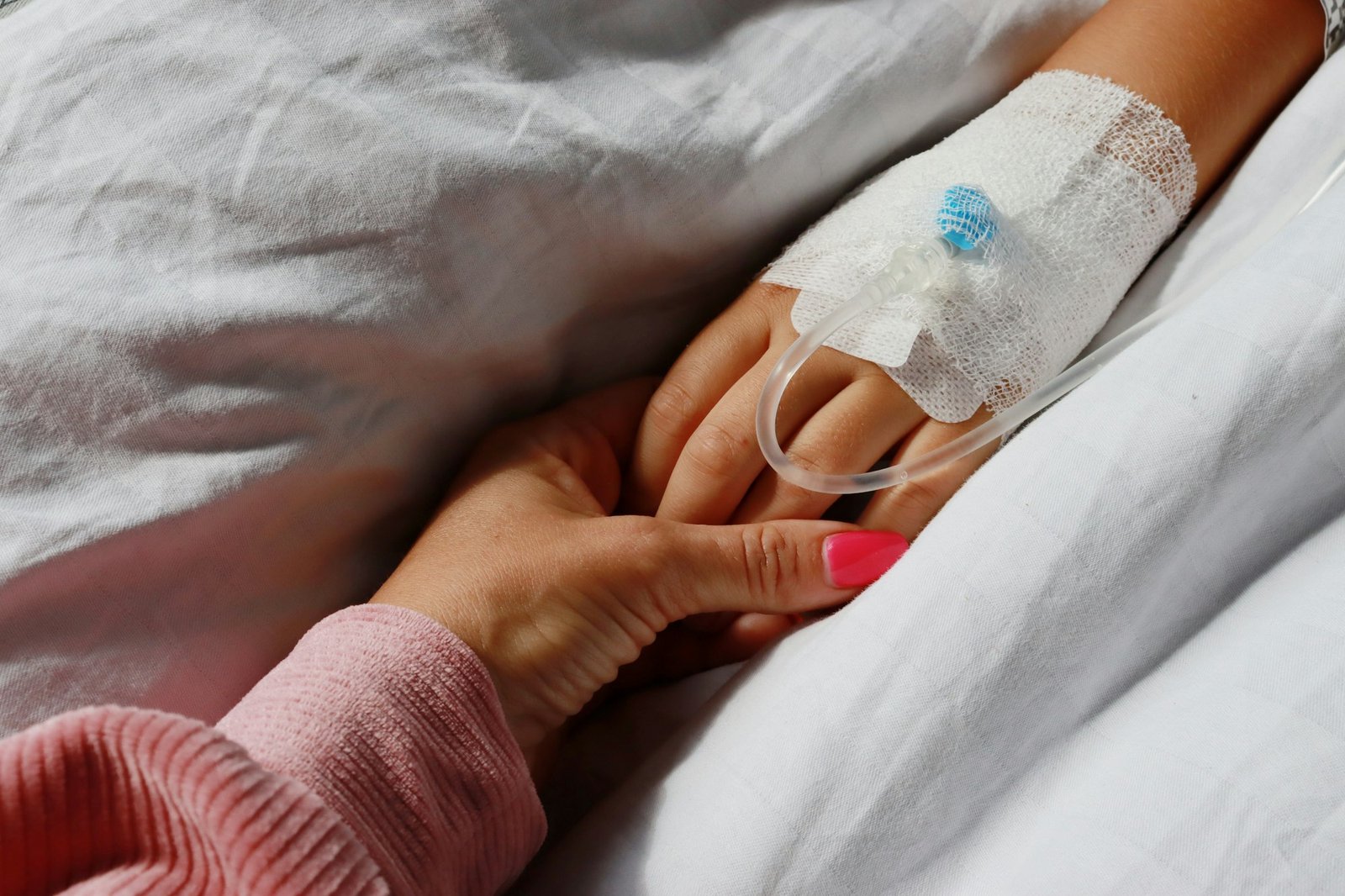 Mom's hand supports the baby in the hospital.